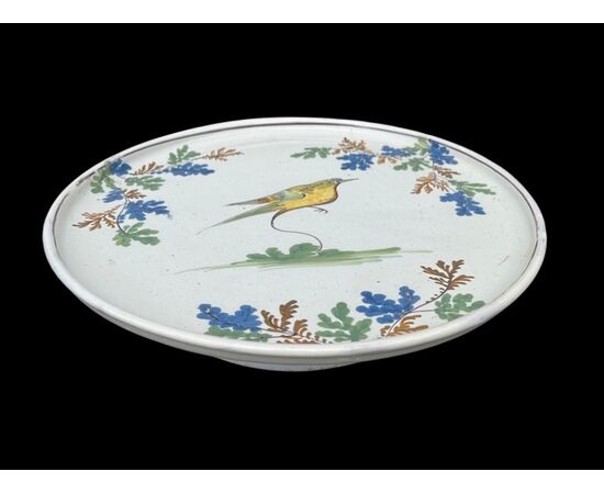 Piatto alzata-tagliere in maiolica con decoro a uccellino e motivi vegetali.Manifattura di Pavia.