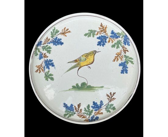Piatto alzata-tagliere in maiolica con decoro a uccellino e motivi vegetali.Manifattura di Pavia.